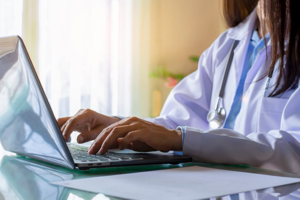 Female doctor in white lab coat typing on laptop at Better Health Whole Wellness Center – Philadelphia ketamine therapy and Spravato provider